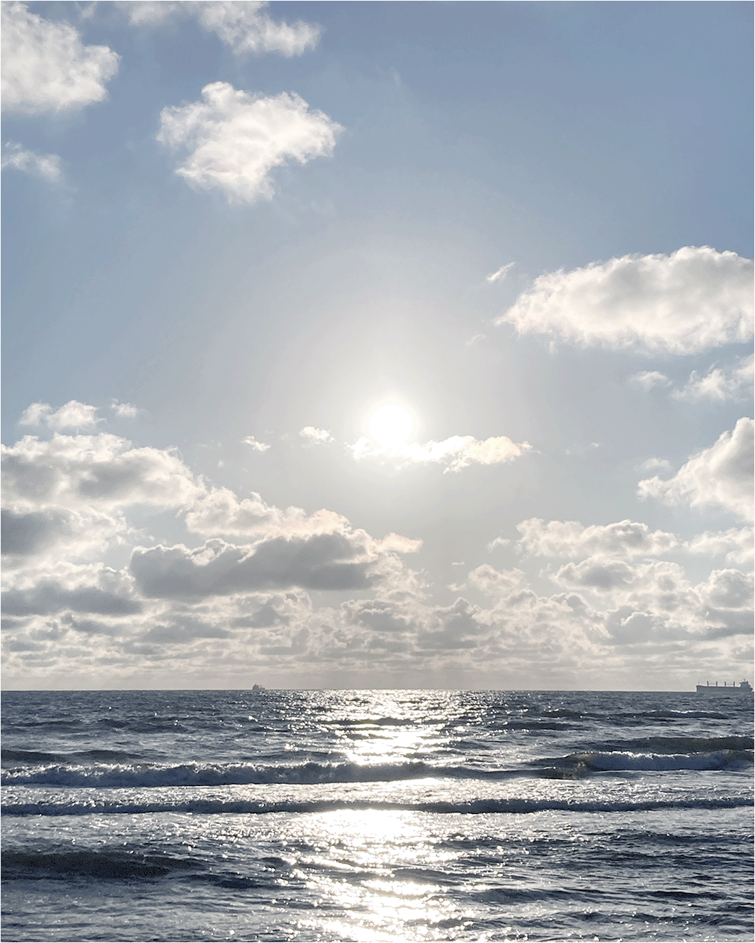 View of the Baltic Sea with single clouds in the sky and the rising sun